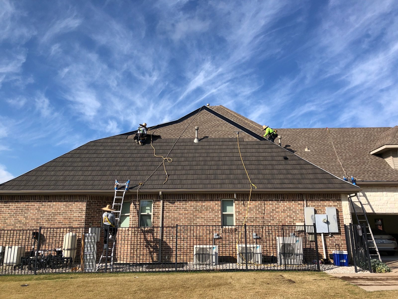 WeatherLok crew in harnesses fastening panels on the hip roof of a brick home
