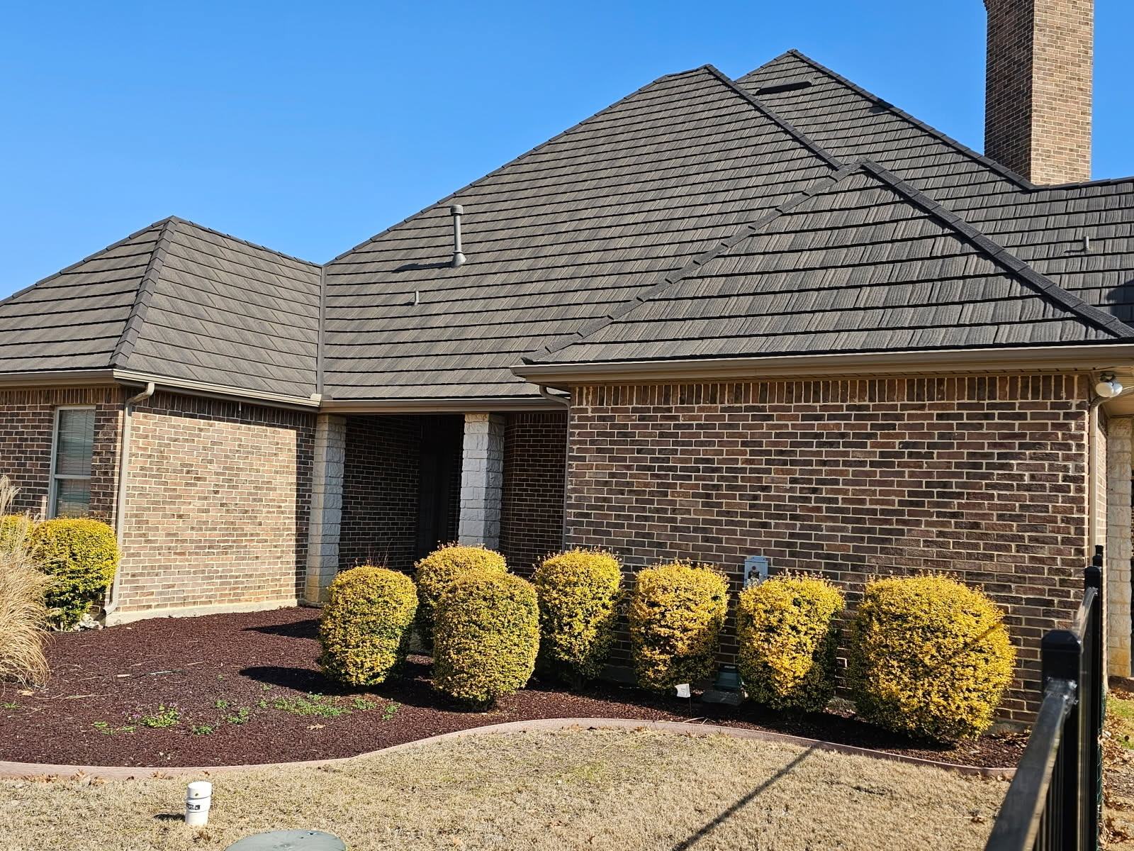 A brick home with a charcoal WeatherLok stone-coated steel shake roof